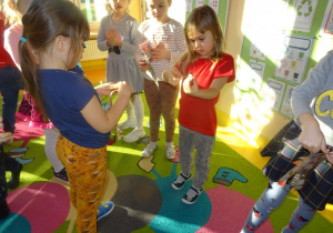 Dzieci zwijają paski gazety w ruloniki.